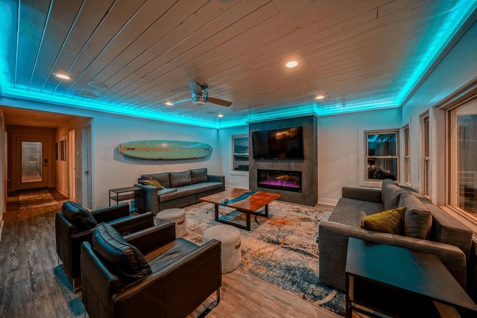 Living room with colour-changing LED cove lighting and a built-in fireplace and TV wall
